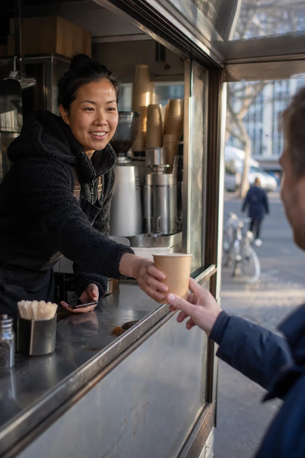 Foodtruck-Mitarbeiter reicht einen Kaffeebecher aus dem Ausgabefenster