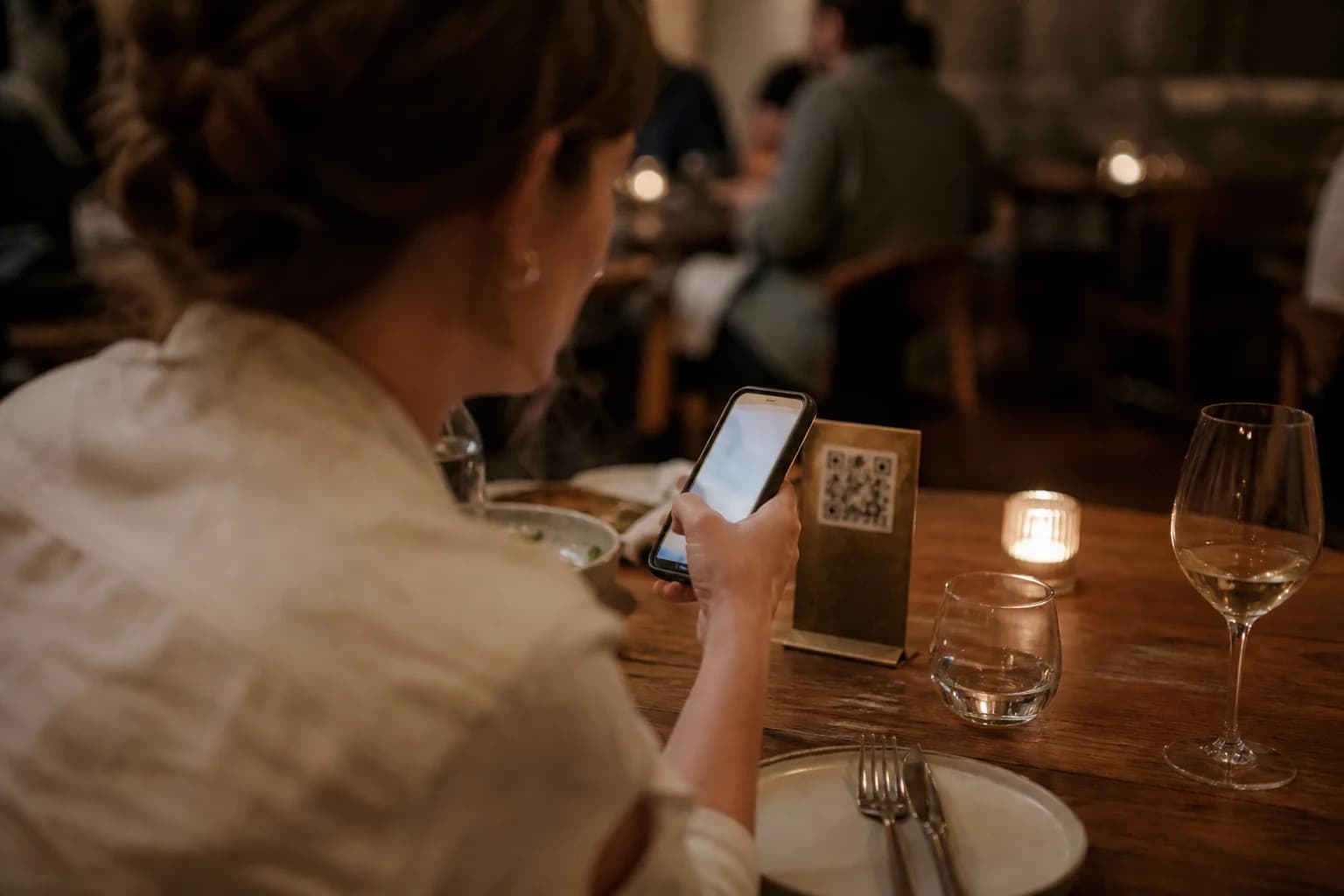 Guest scans a QR stand at the restaurant table with a smartphone