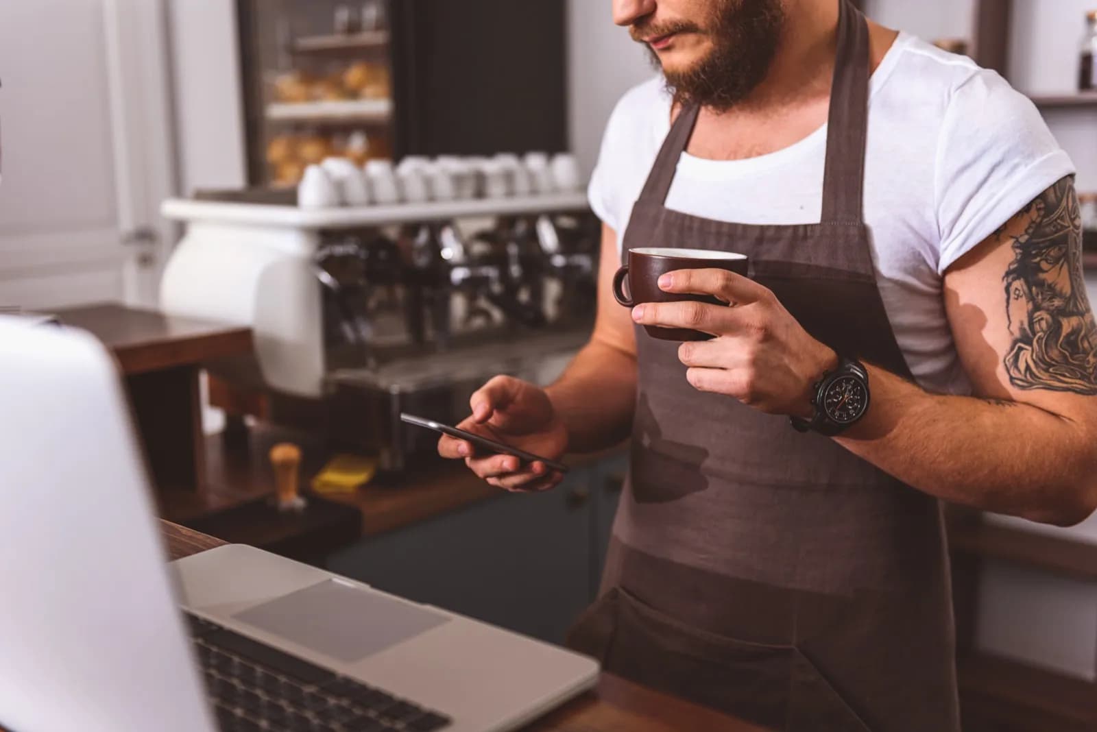 Barista tippt auf Smartphone in Bäckerei