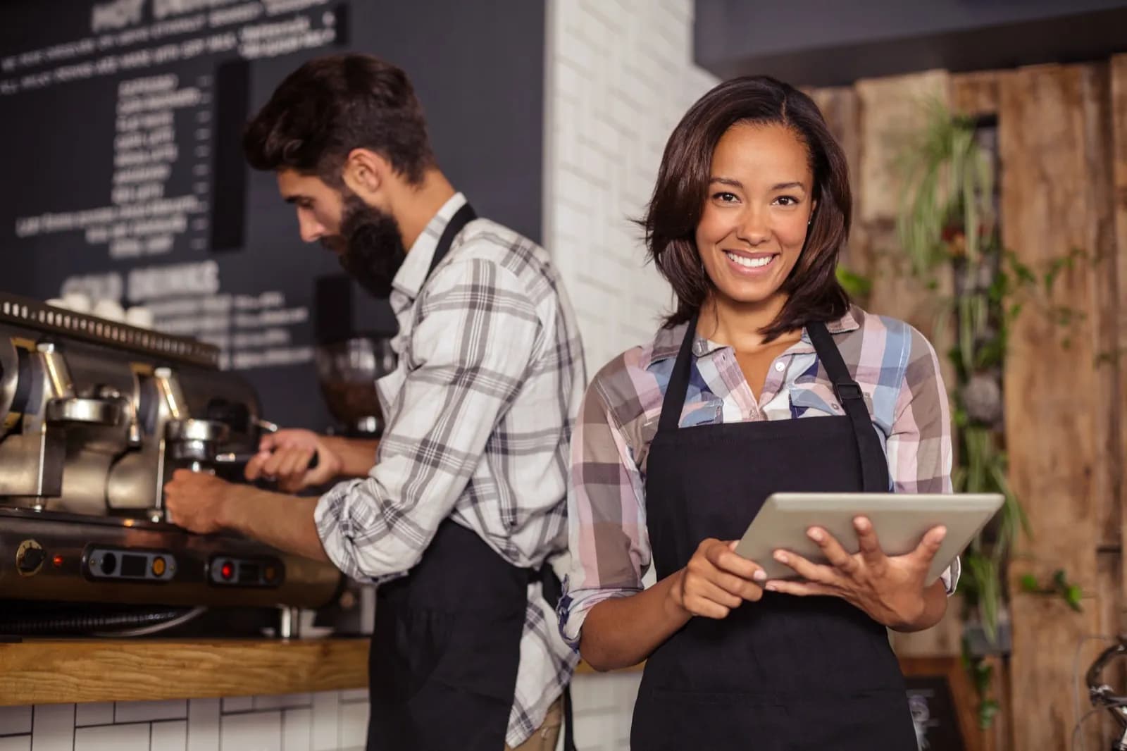 Barista-Team arbeitet mit Tablet an Kaffeemaschine