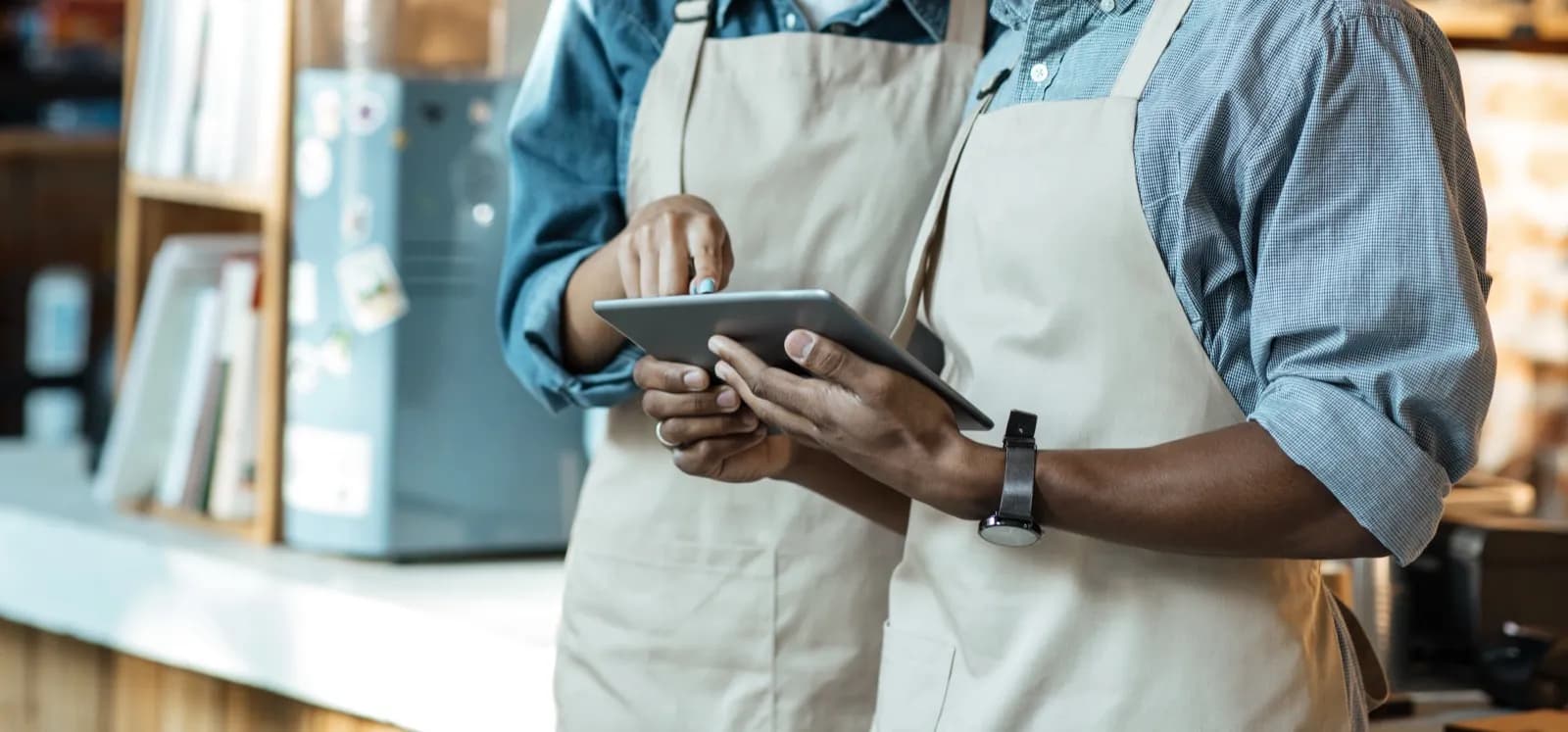 Zwei Kellner schauen gemeinsam auf Tablet